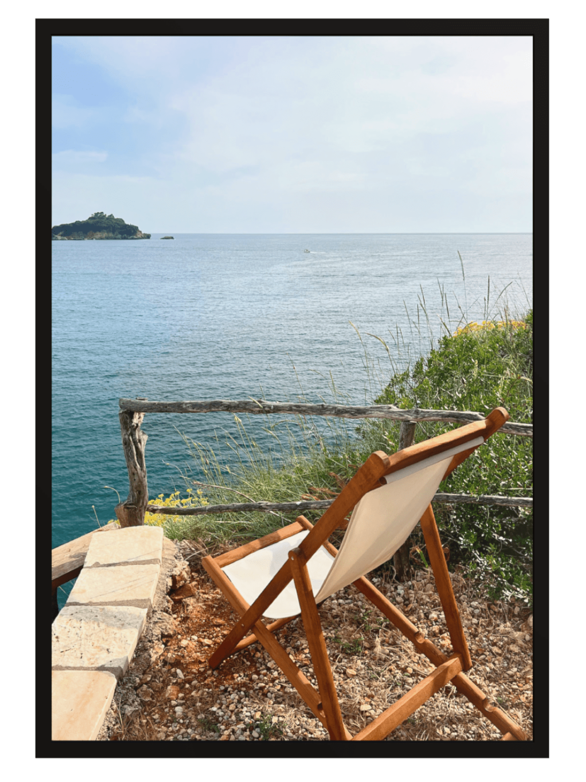 Wooden chair with white cushion overlooking a body of water and a small island.