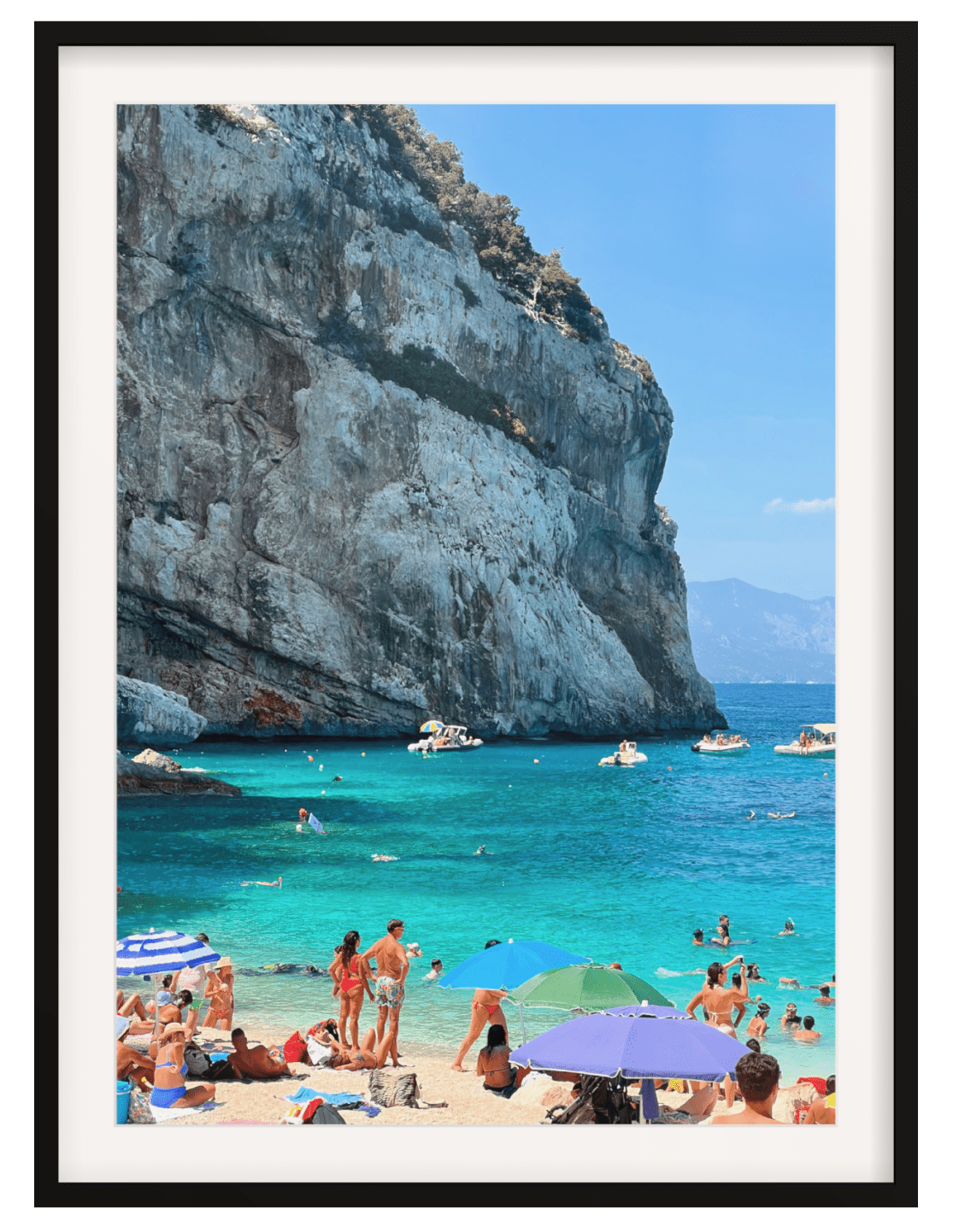 Sardinia beach wall art in black frame with thick white mat featuring turquoise water and pebbles