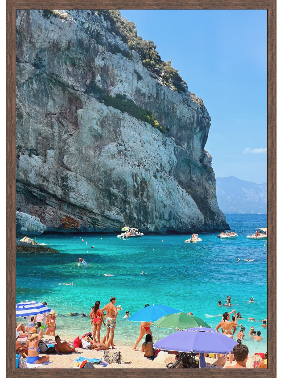Vertical Sardinia beach wall art in dark brown wooden frame with green vegetation on limestone cliff
