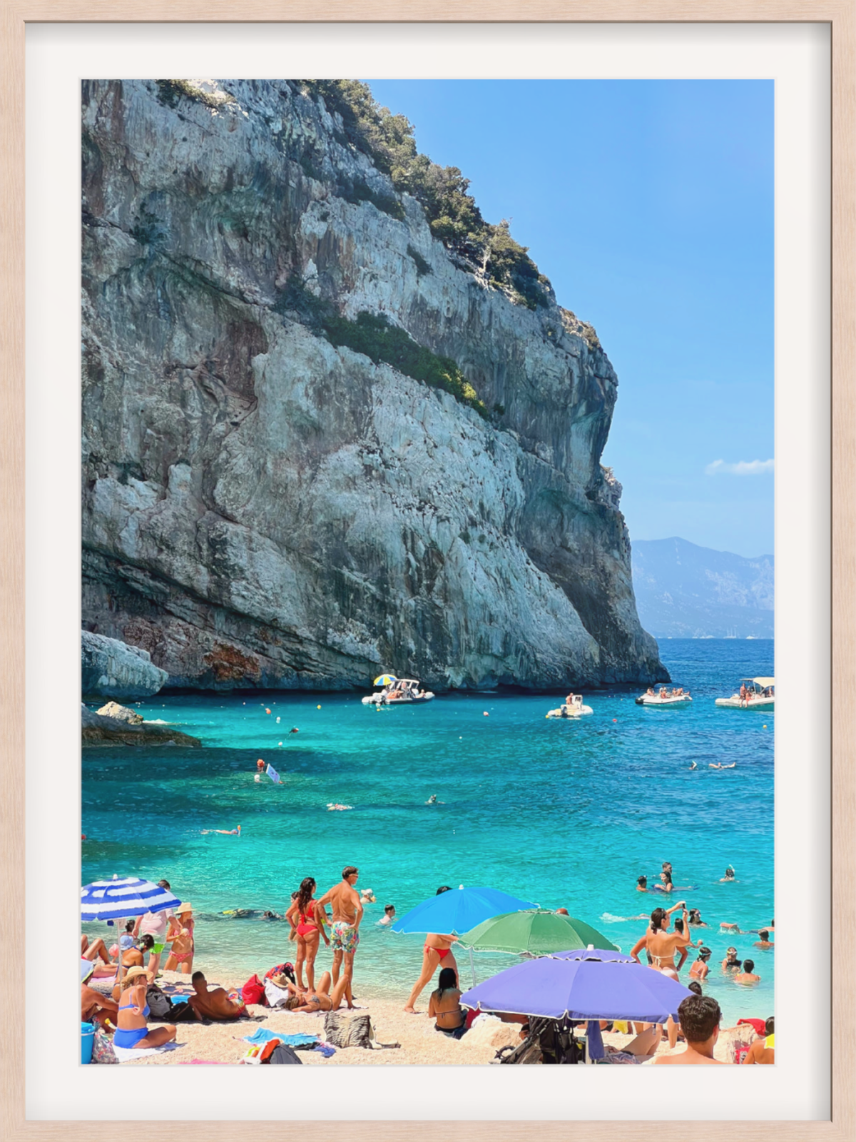 Gallery-style Sardinia wall art in light wood frame with white mat featuring vibrant turquoise sea