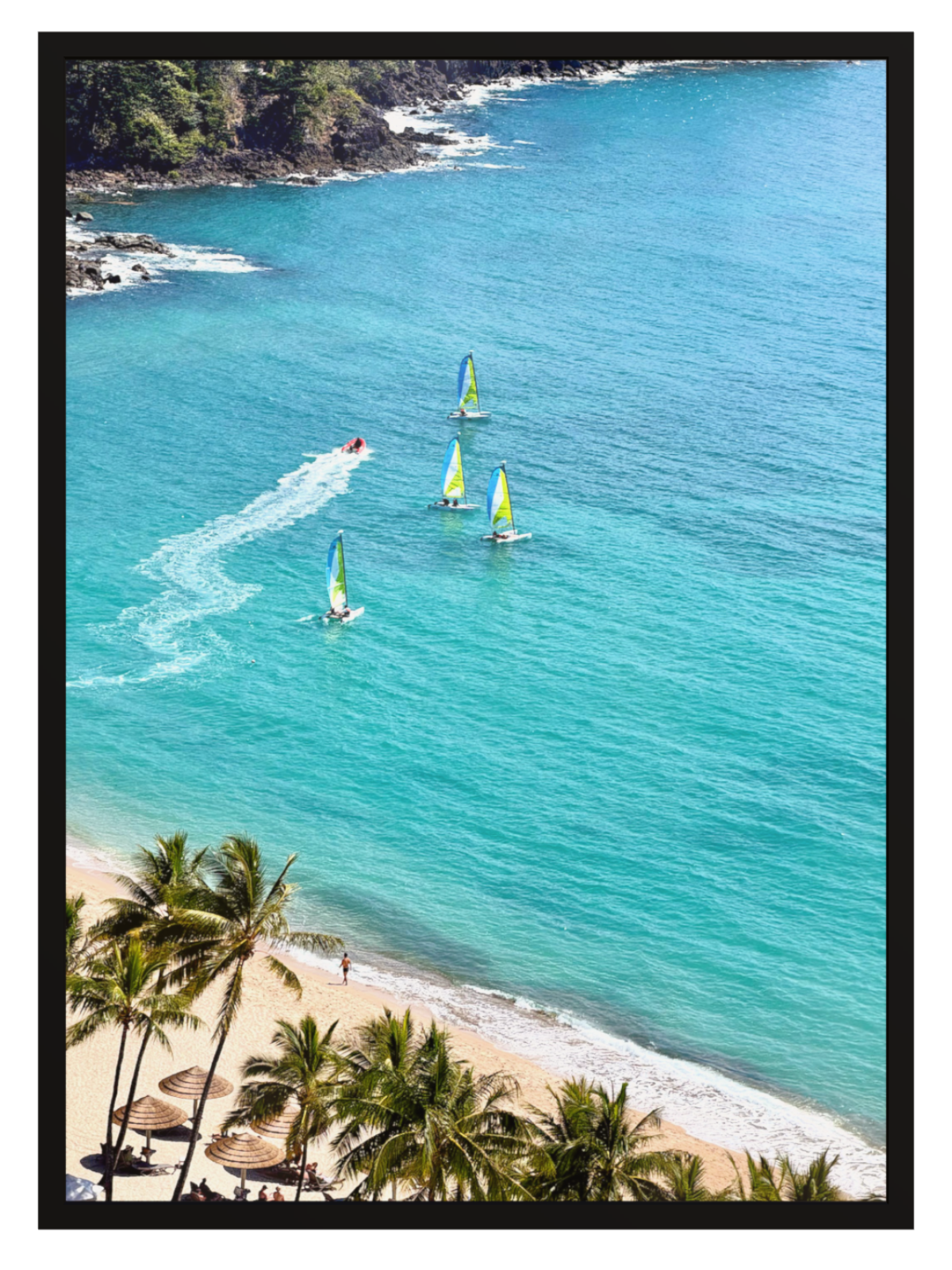 A framed photographic print of a tropical beach scene with turquoise ocean water, sailboats, palm trees, and a sandy shoreline.