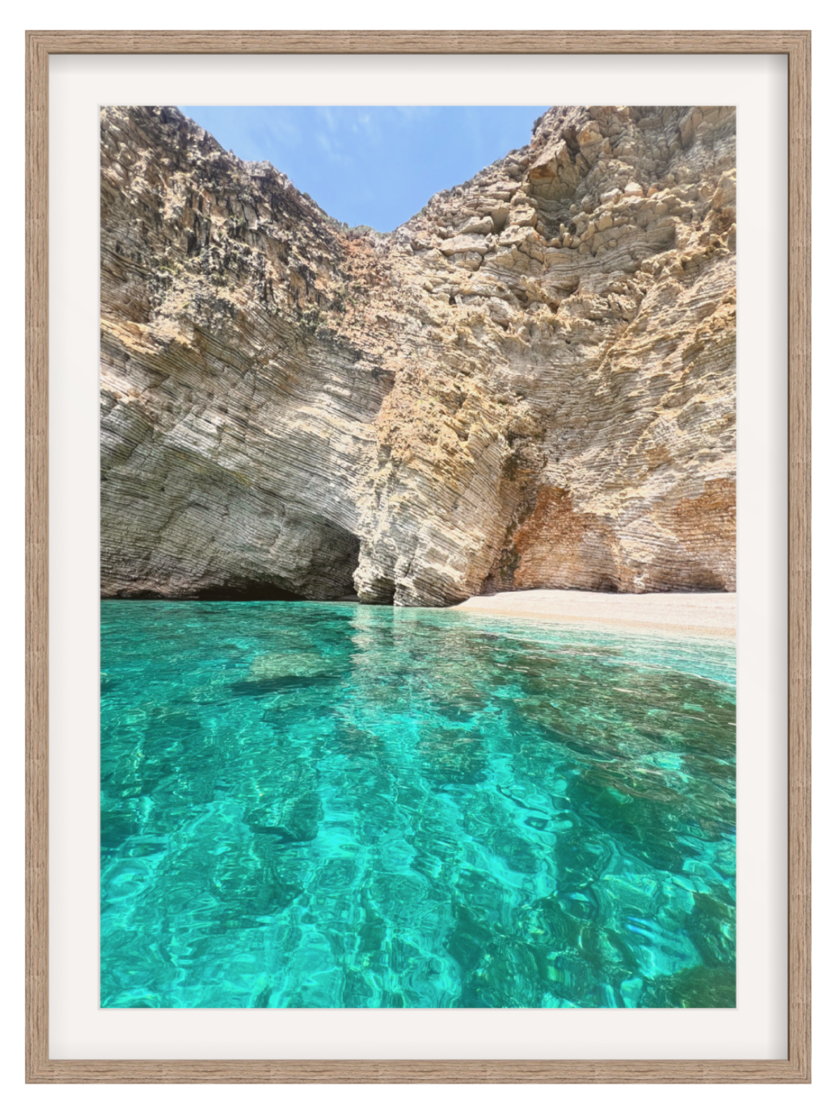 Framed photograph of a rocky coastline with clear blue water.