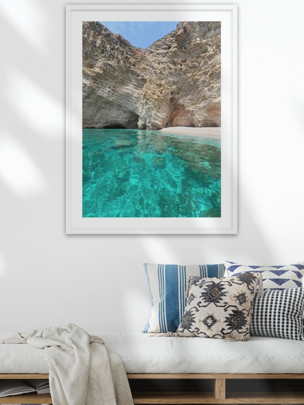 Framed artwork of a rocky cove with clear blue water in a modern living room.