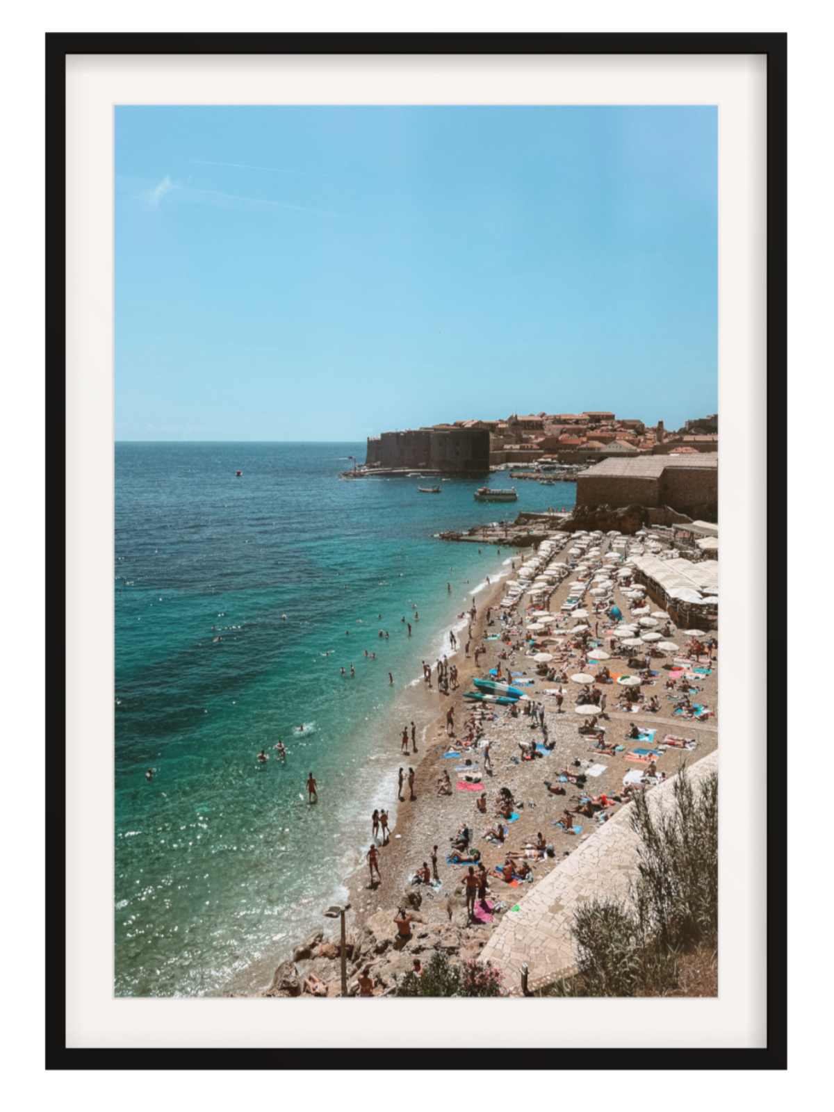 Framed photograph of a beach scene with people and umbrellas, featuring a castle on an island.