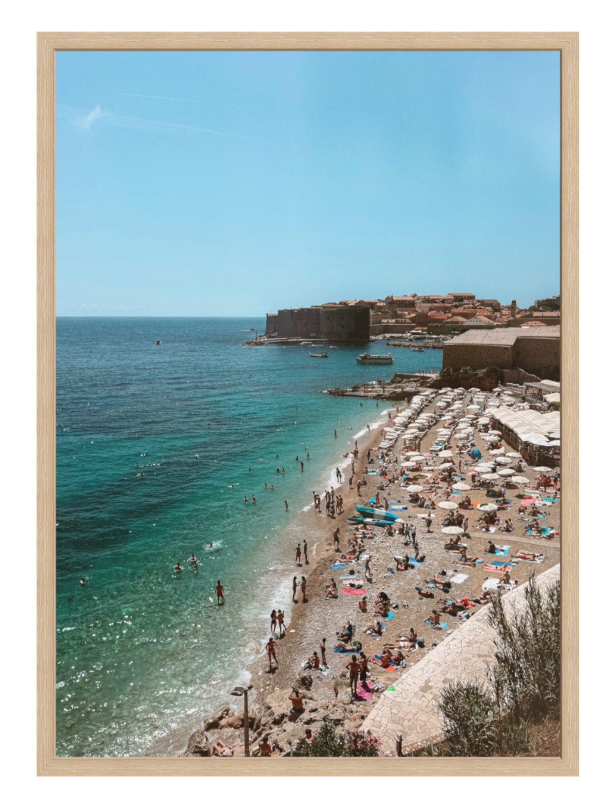 Beach scene with people and umbrellas, clear blue water, and a wooden frame.