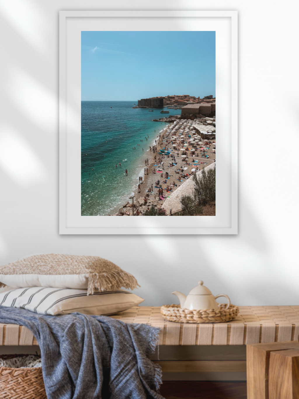 Framed photograph of a beach scene on a wall above a wooden table.