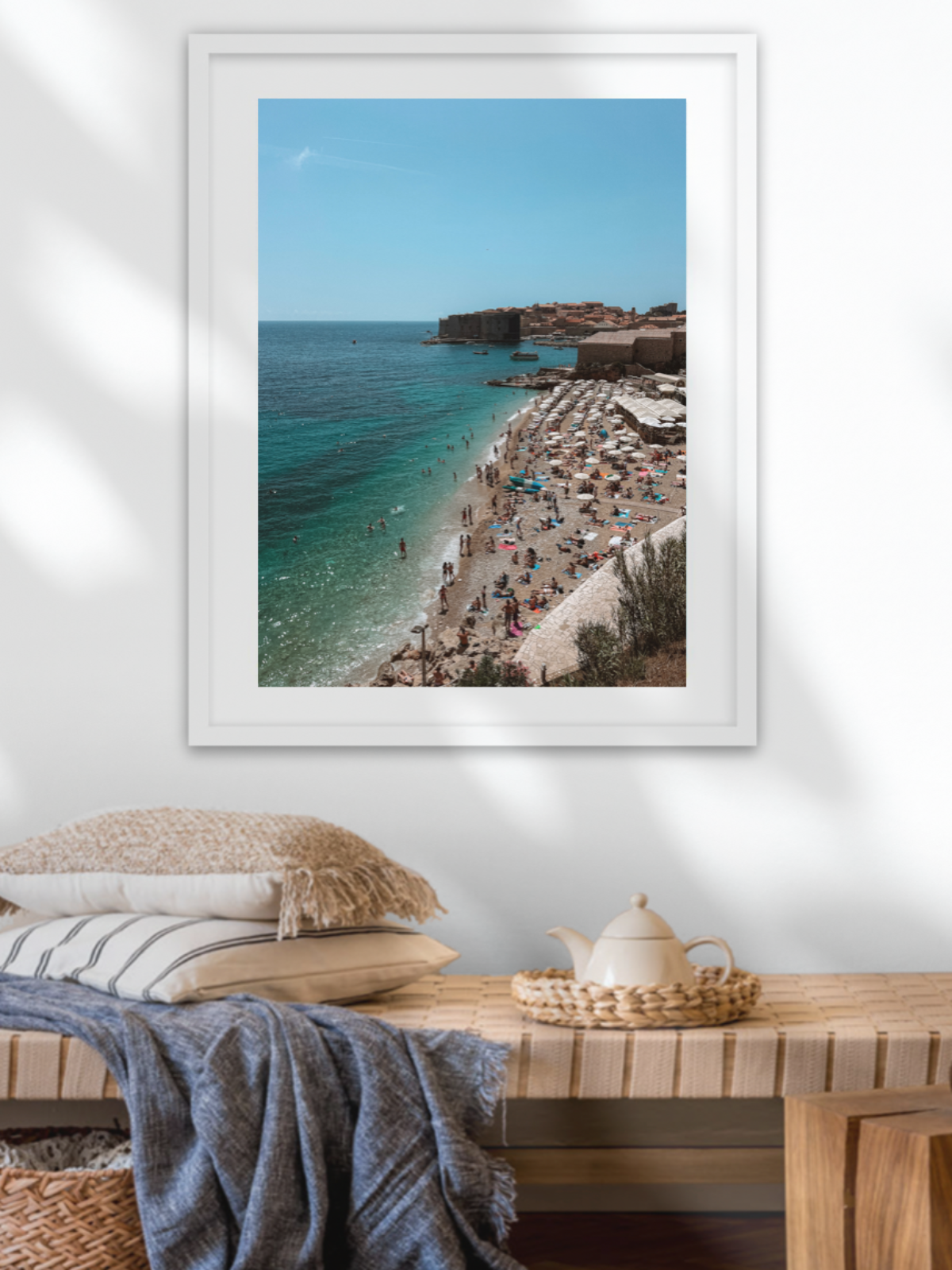 Framed photograph of a beach scene on a wall above a wooden table.