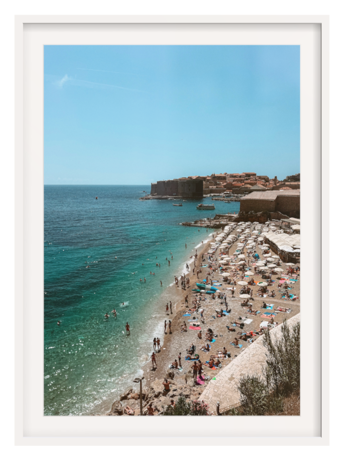 Beach scene with people, umbrellas, and a clear blue sky.