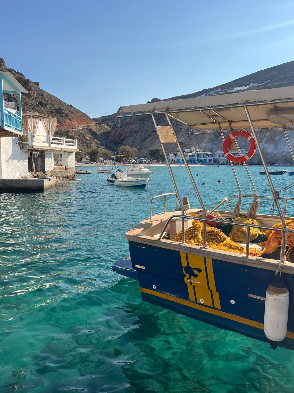 Boat docked in a harbor with clear blue water and a scenic background