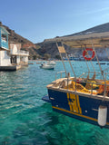 Boat docked in a harbor with clear blue water and a scenic background