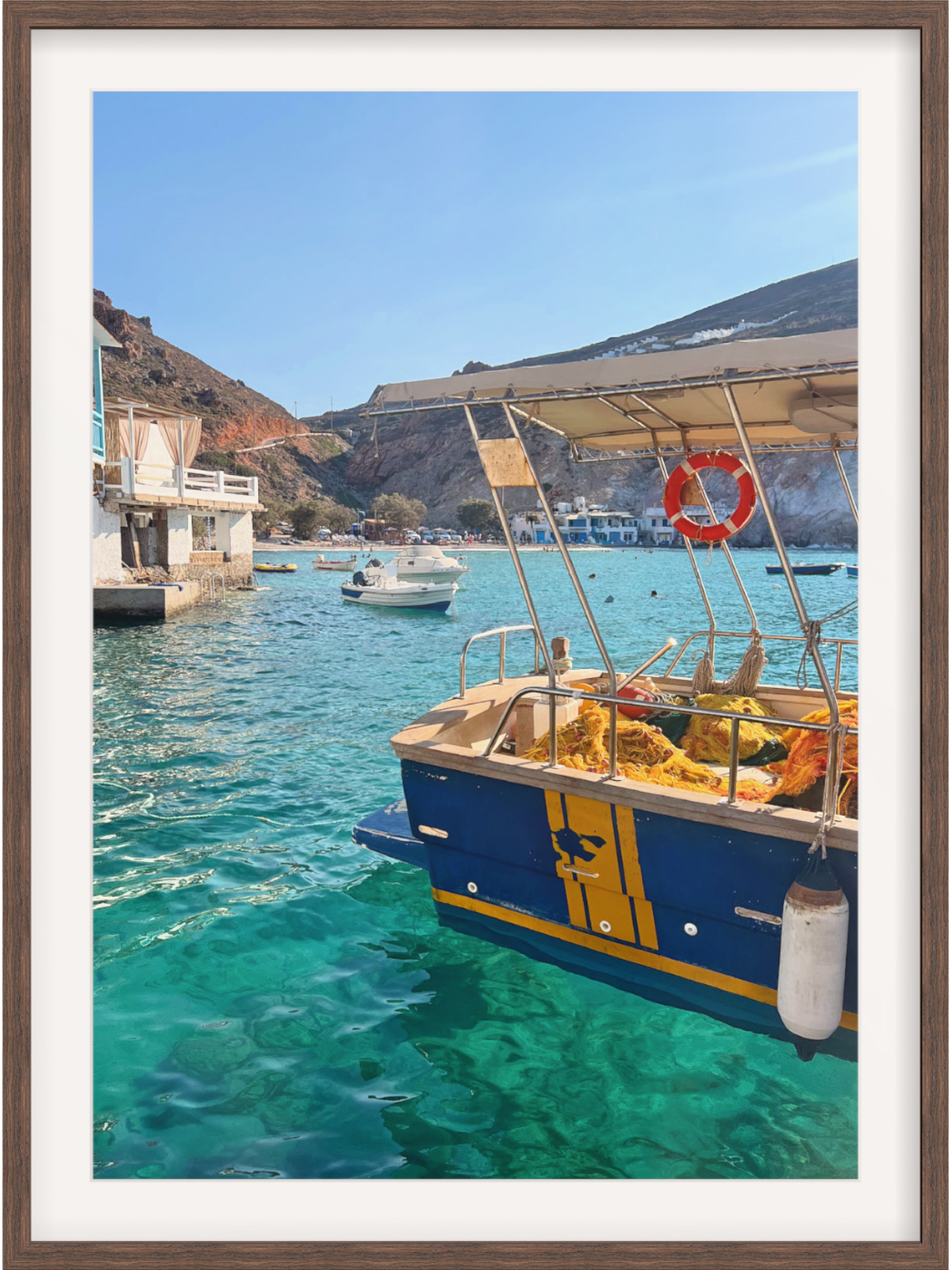 Blue and yellow boat in a harbor with clear blue water and a mountainous background.