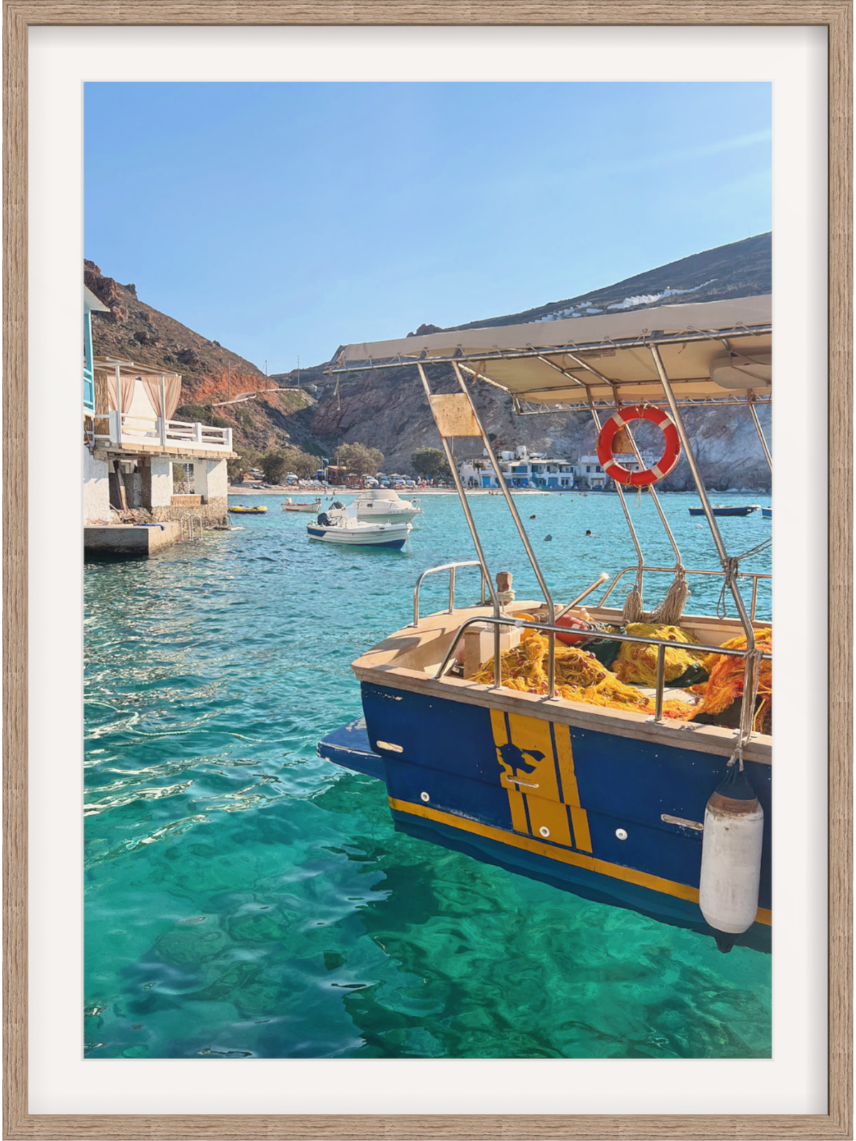 Blue and yellow boat in a harbor with clear blue water and mountains in the background.
