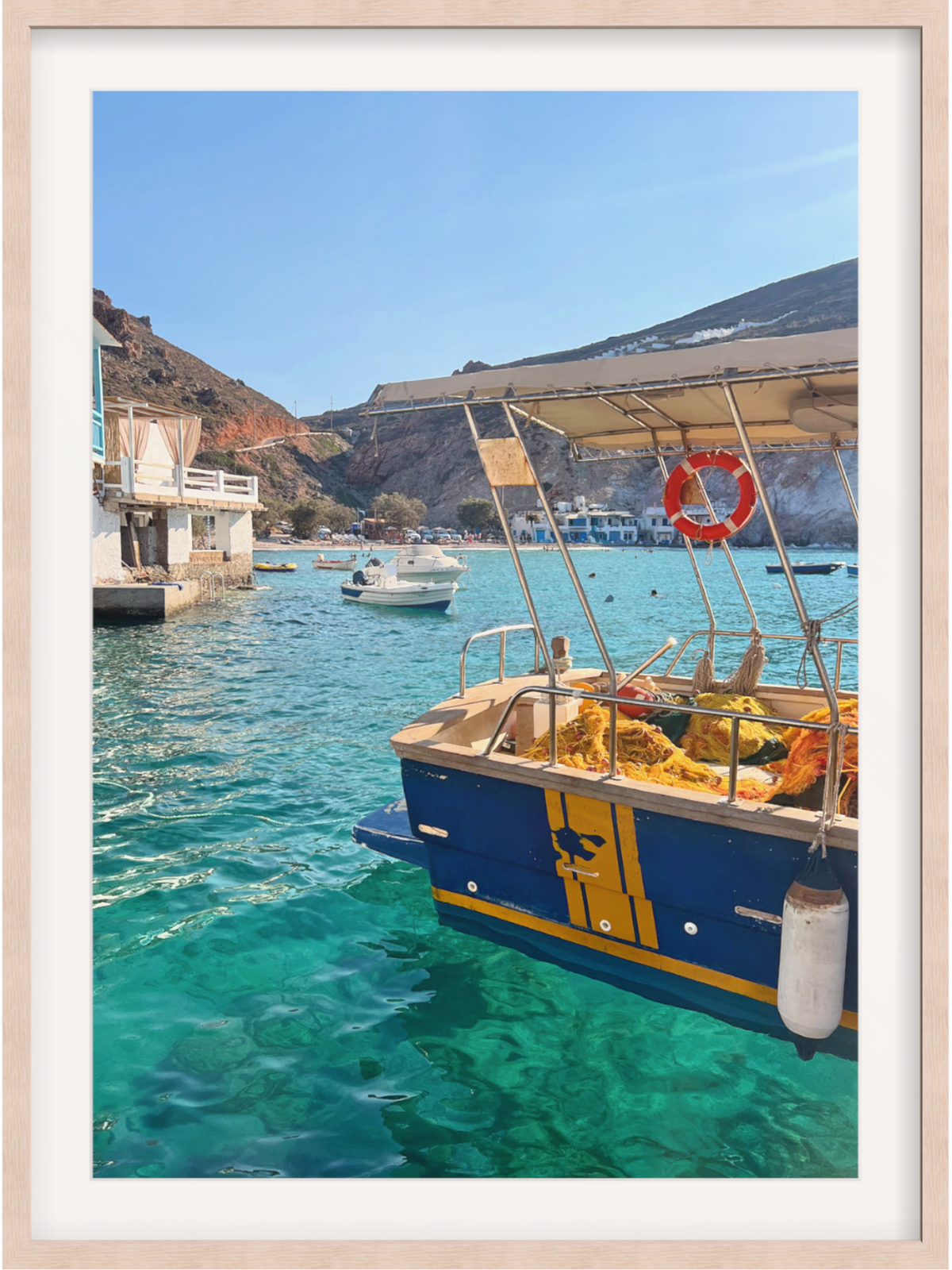 Blue and yellow boat in a harbor with clear blue water and mountains in the background.