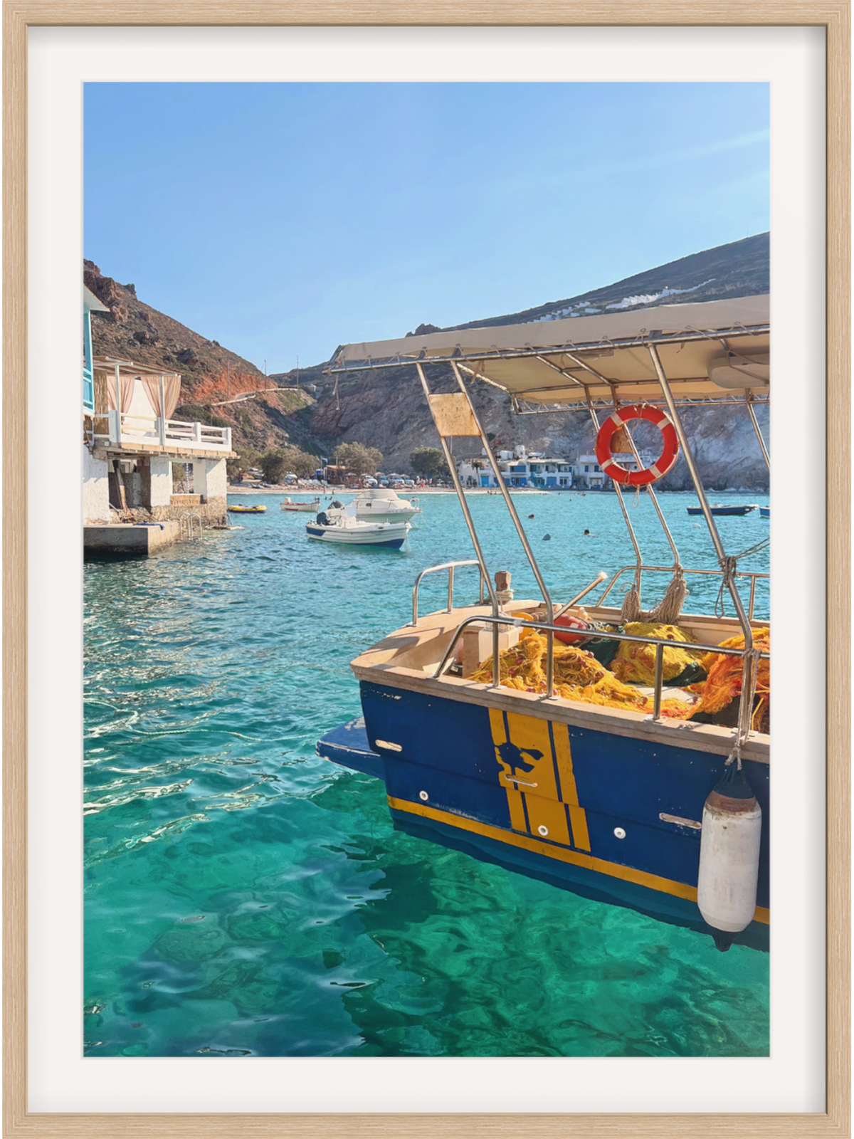 Blue and yellow boat in a harbor with clear blue water and a mountainous background.