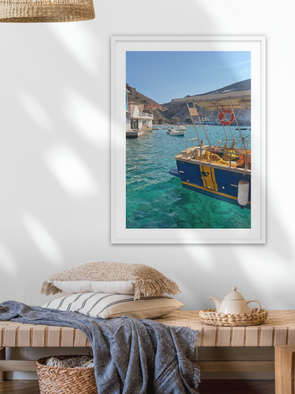 Framed photograph of a coastal scene with boats on a wall above a wooden bench.