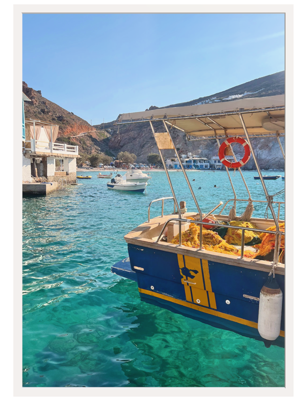 Boat docked in a harbor with clear blue water and mountains in the background