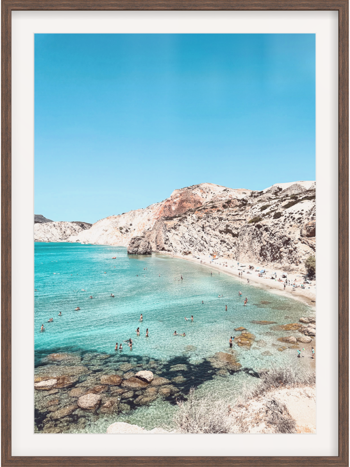 Framed photograph of a beach with clear blue water and rocky cliffs.