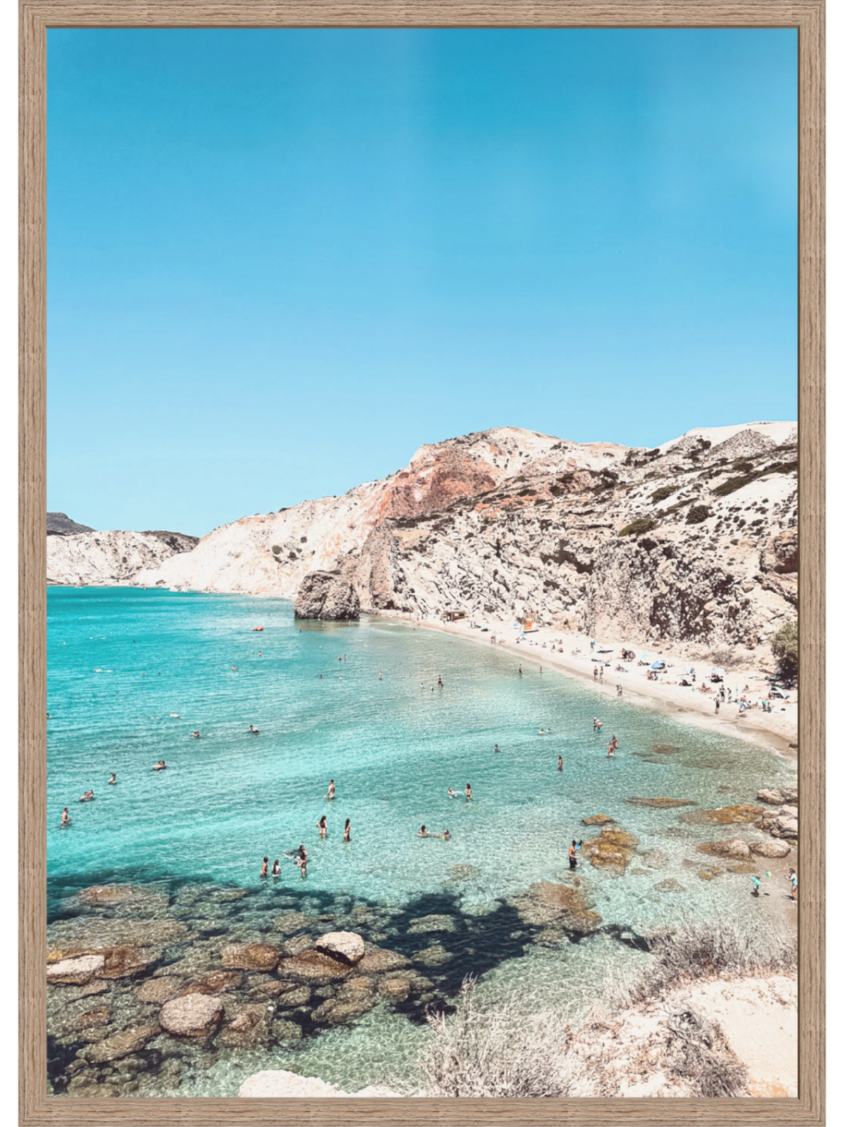 Framed photograph of a beach with clear blue water and rocky cliffs.
