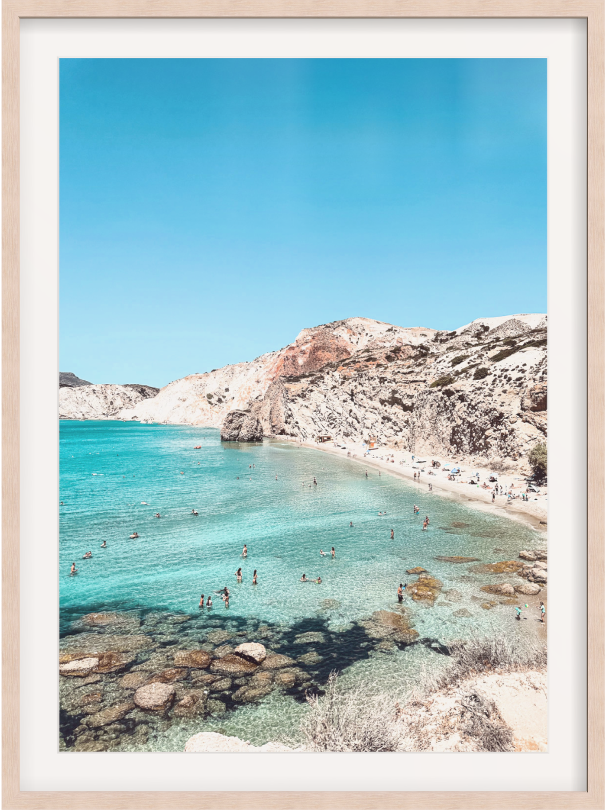 Framed photograph of a beach with clear blue water and rocky cliffs.