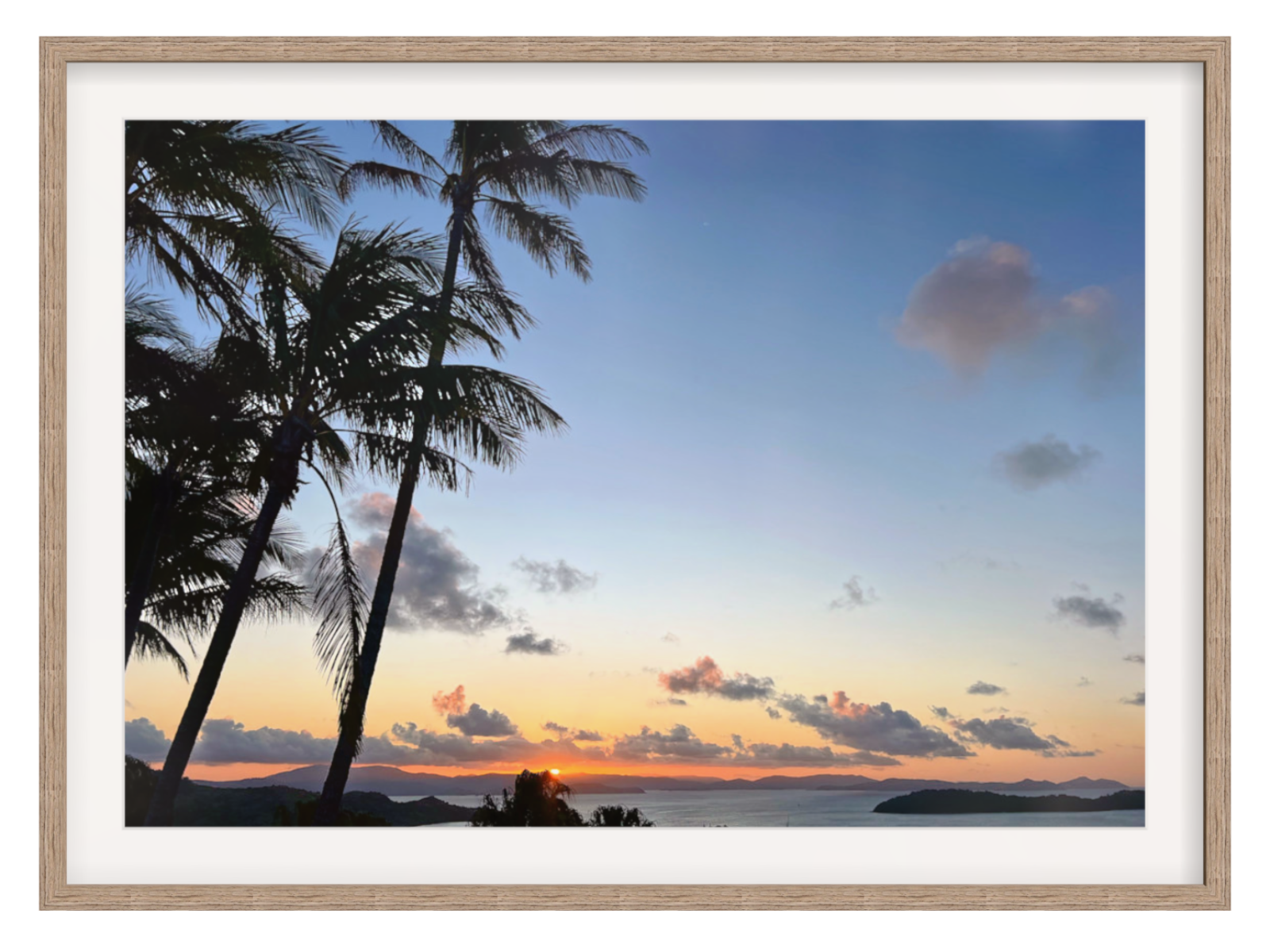 Framed artwork of a sunset with palm trees and a clear sky.