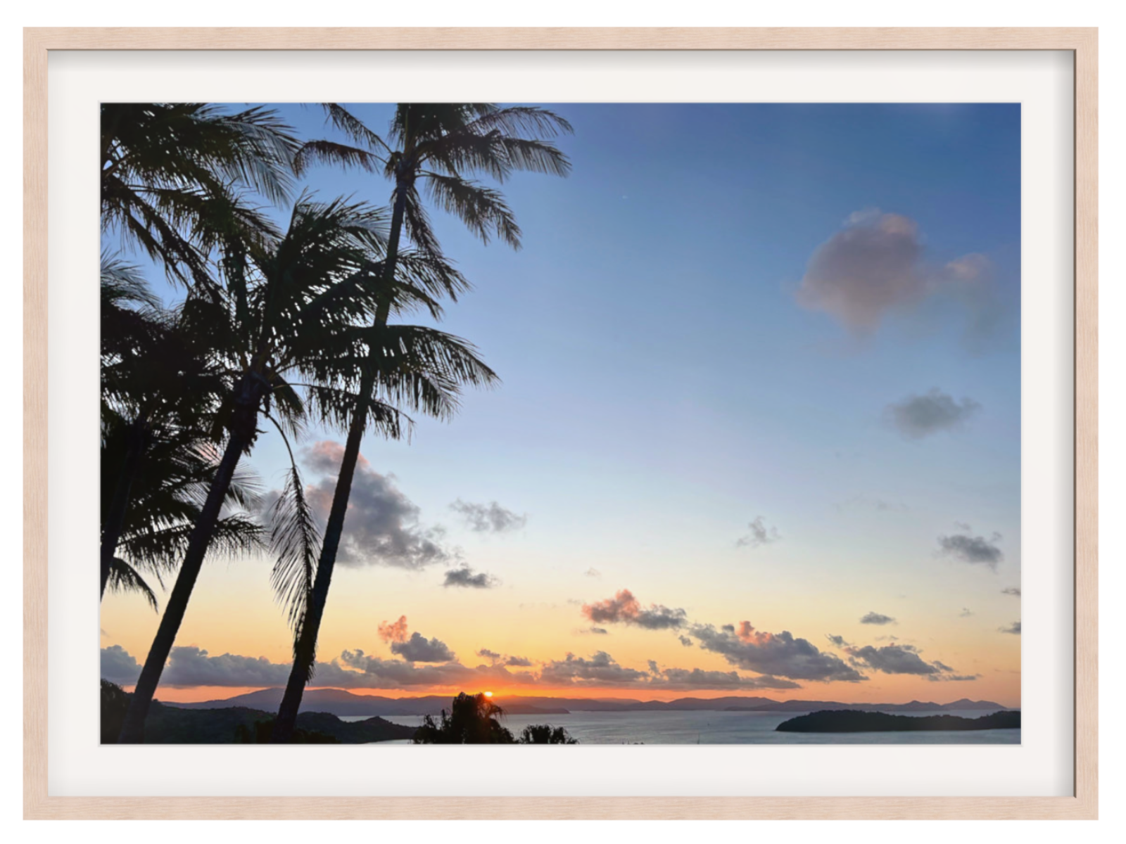 Framed photograph of a sunset with palm trees and a clear sky.