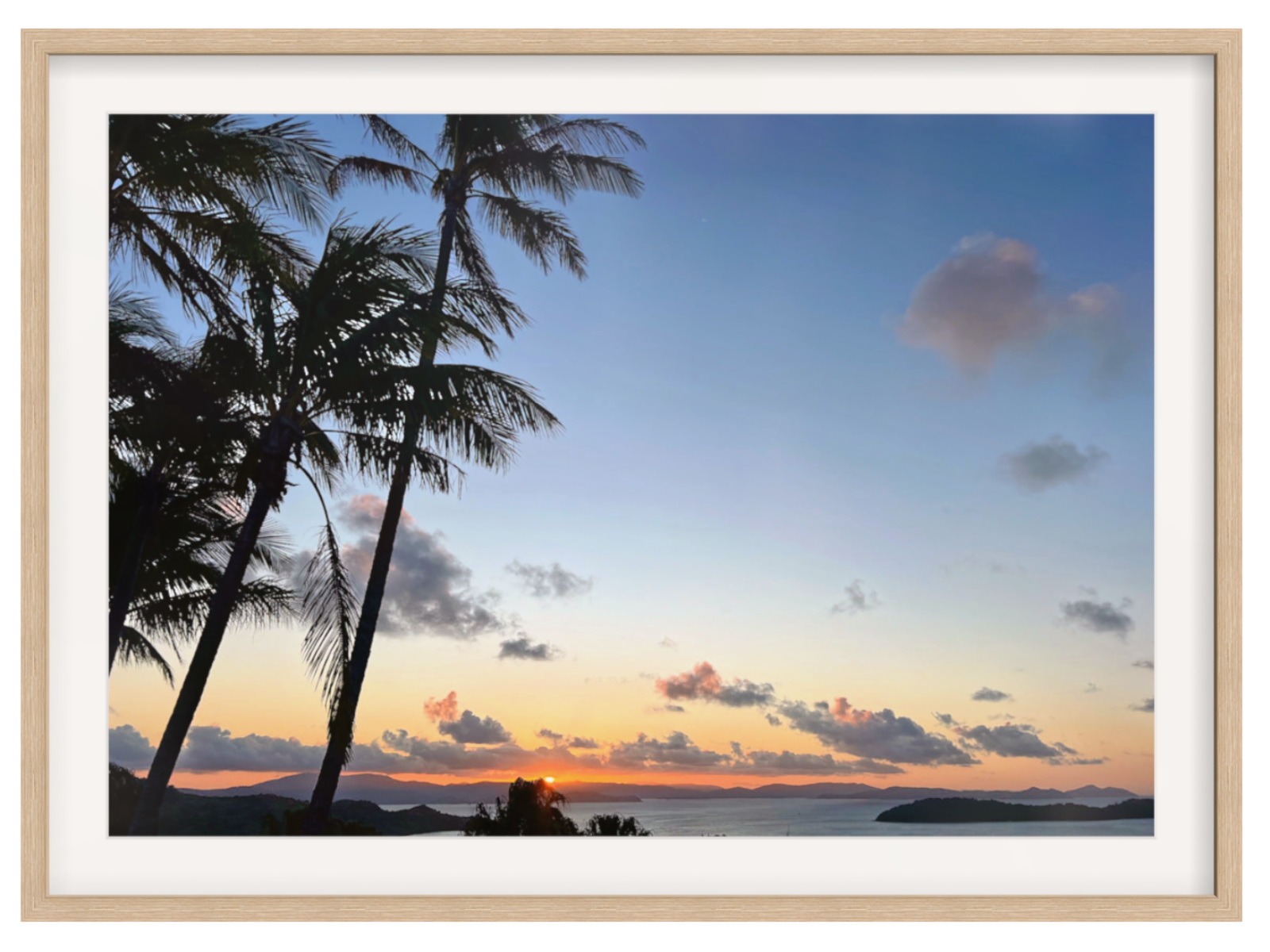 Framed artwork of a sunset with palm trees and ocean.