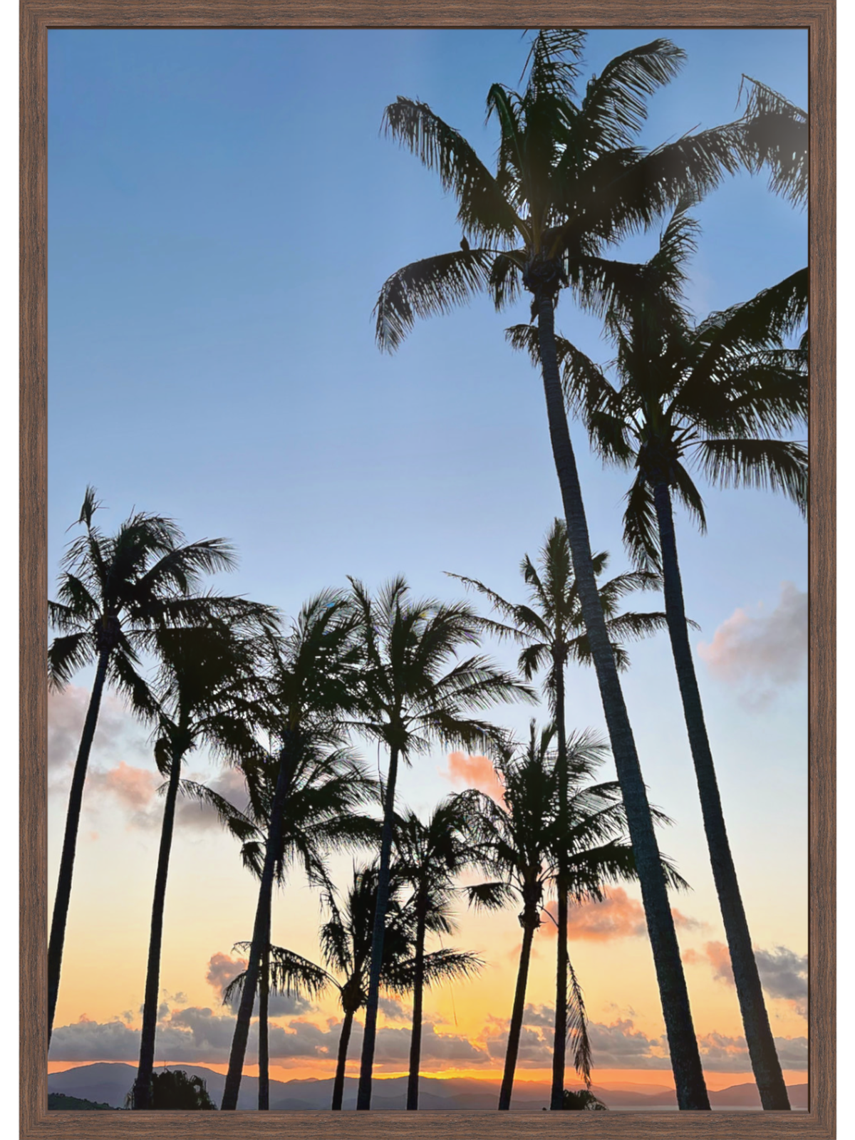Framed artwork of palm trees against a sunset sky