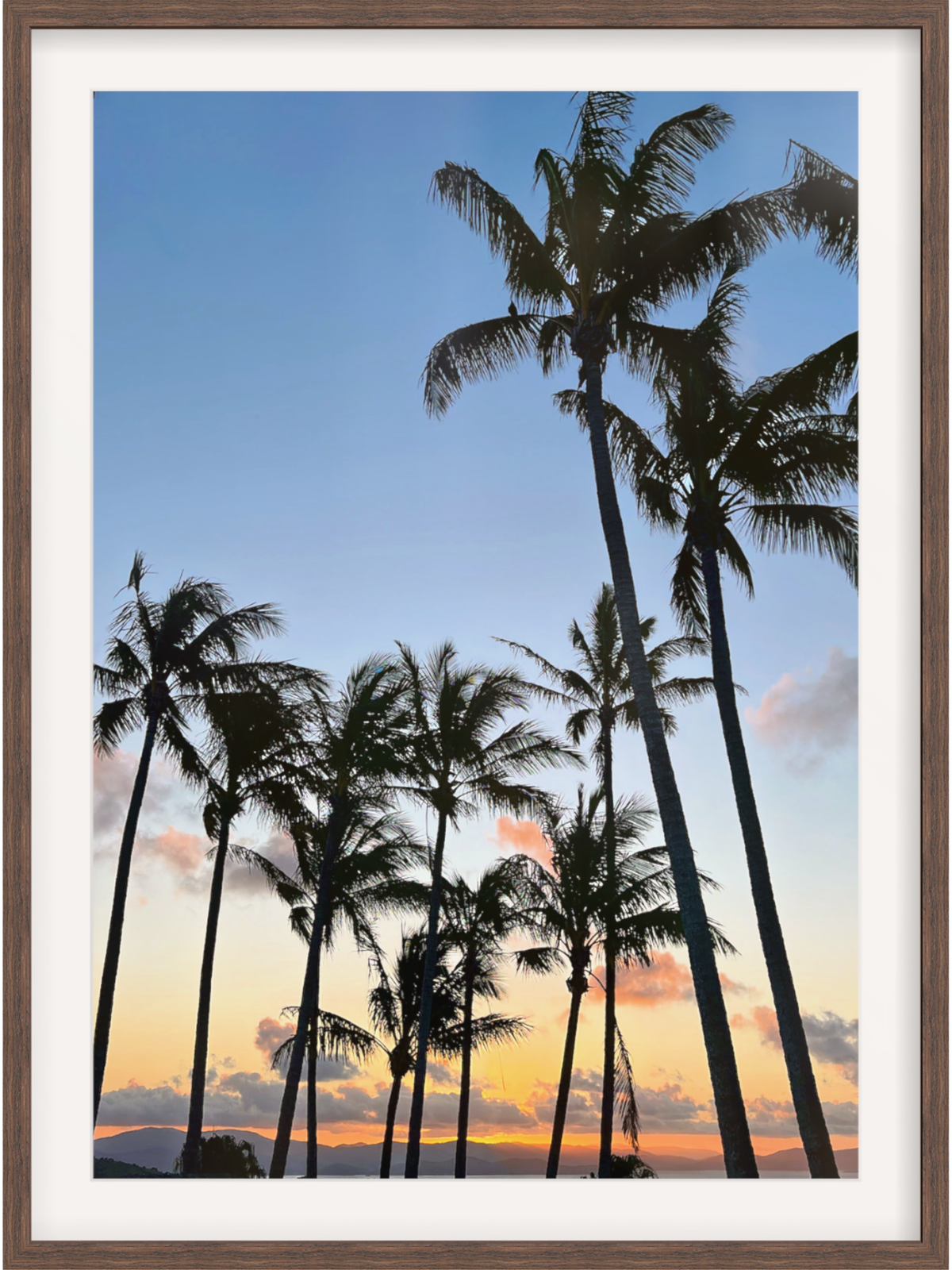 Framed artwork of palm trees against a sunset sky