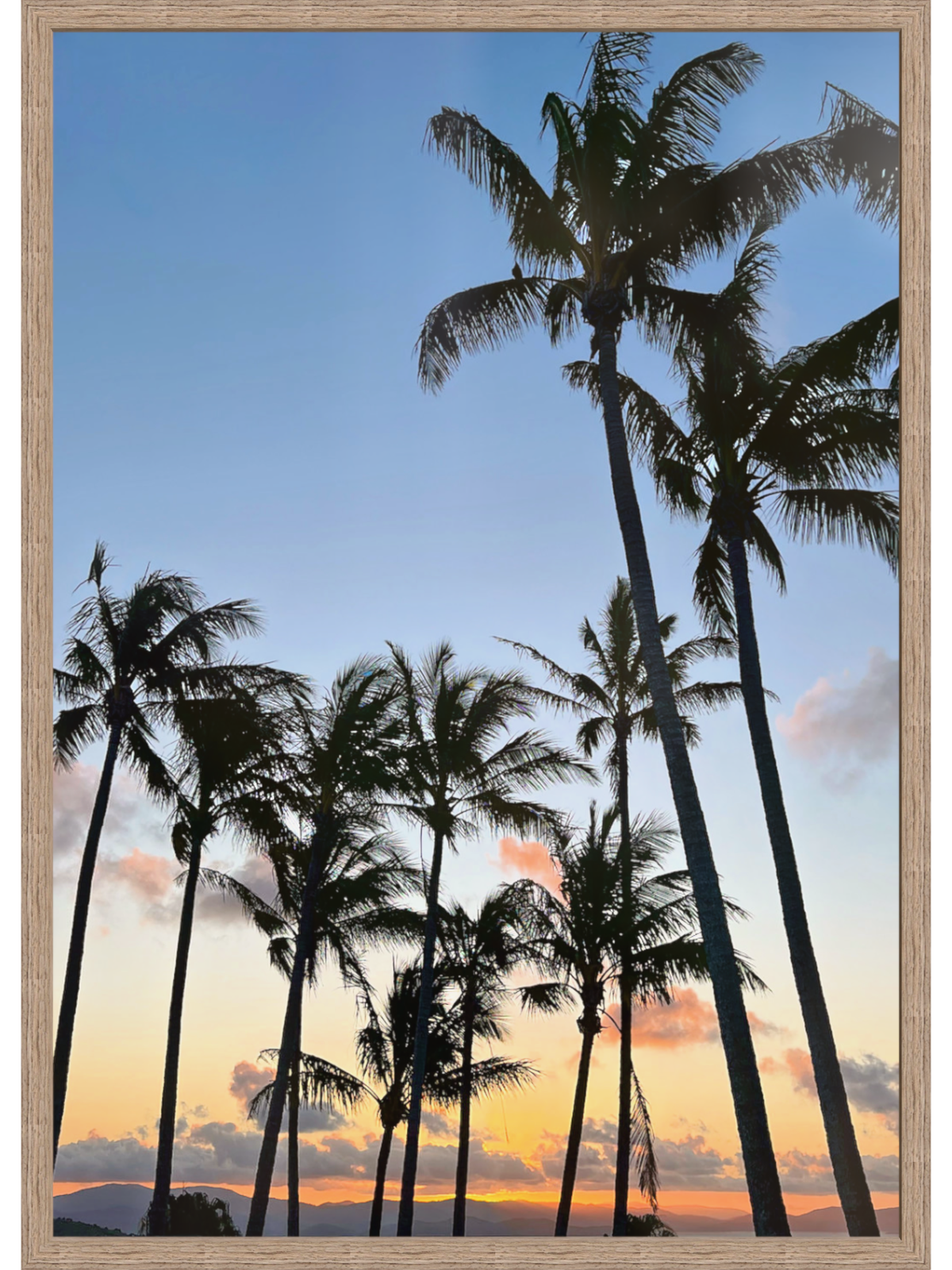 Silhouettes of palm trees against a colorful sunset sky with a wooden frame.