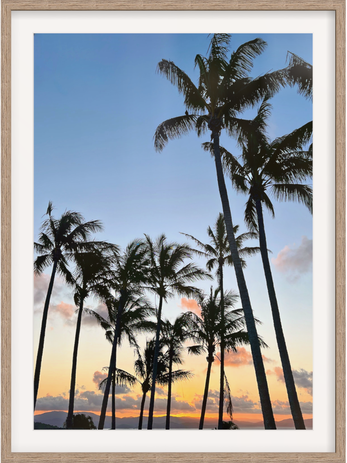 Framed artwork of palm trees against a sunset sky