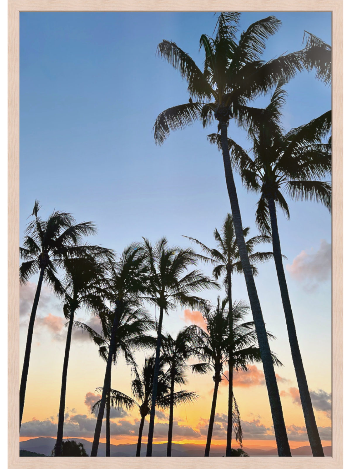 Framed artwork of palm trees against a sunset sky
