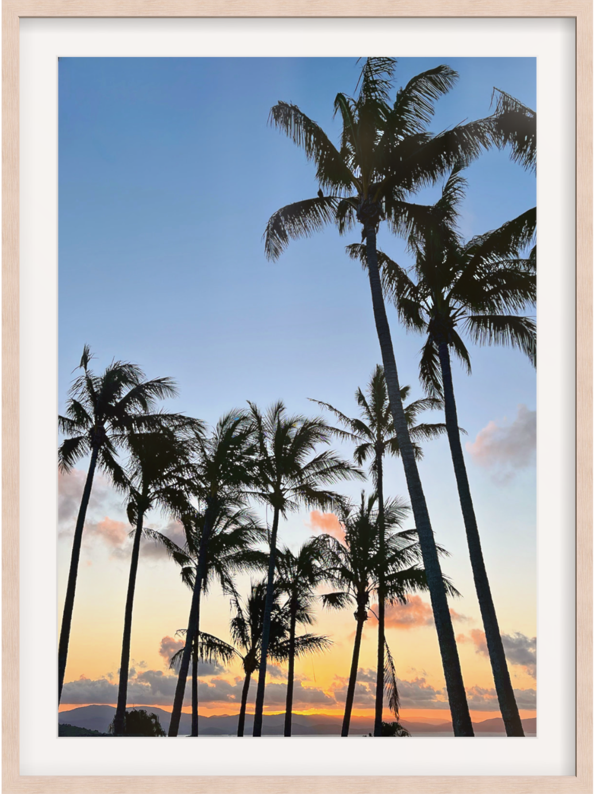 Framed artwork of palm trees against a sunset sky