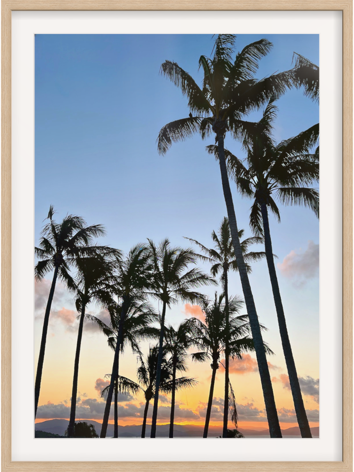 Framed artwork of palm trees against a sunset sky