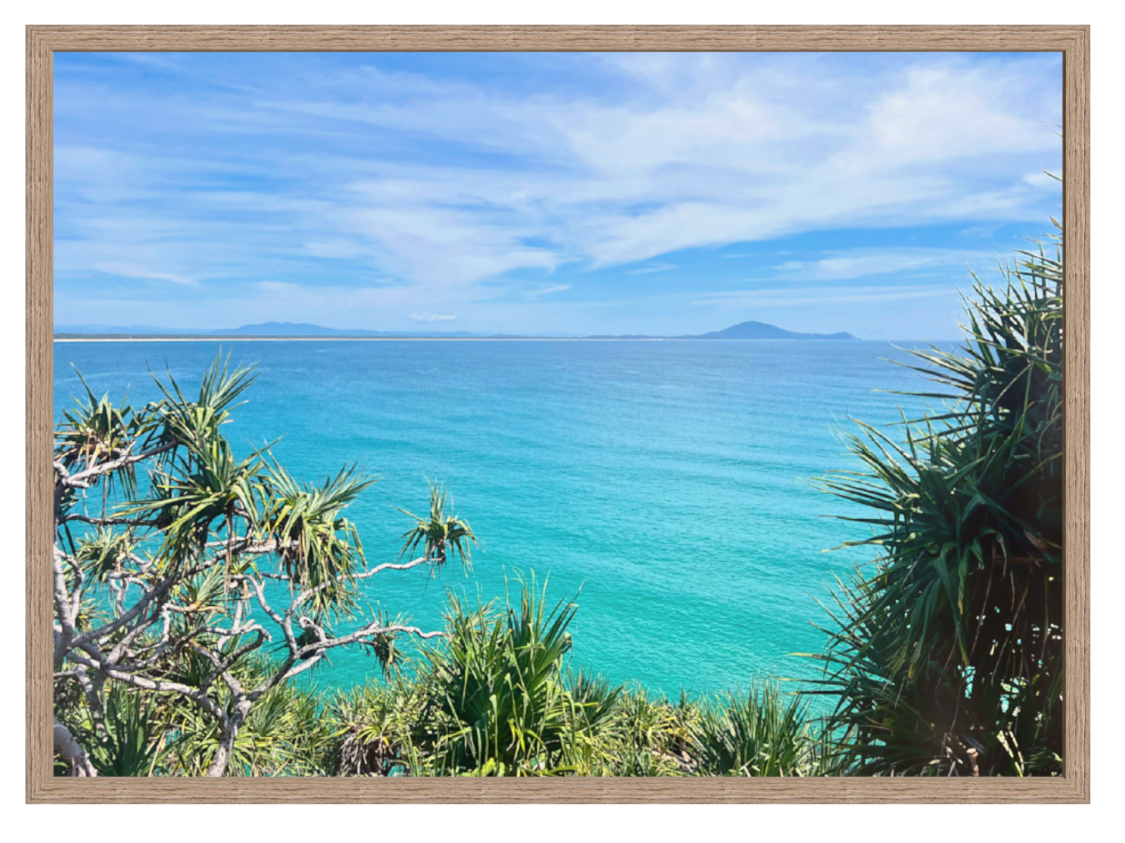 Framed photograph of a tropical beach with clear blue water and greenery.