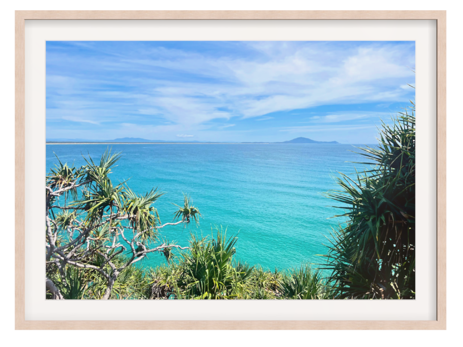 Framed photograph of a tropical beach with turquoise water and greenery.