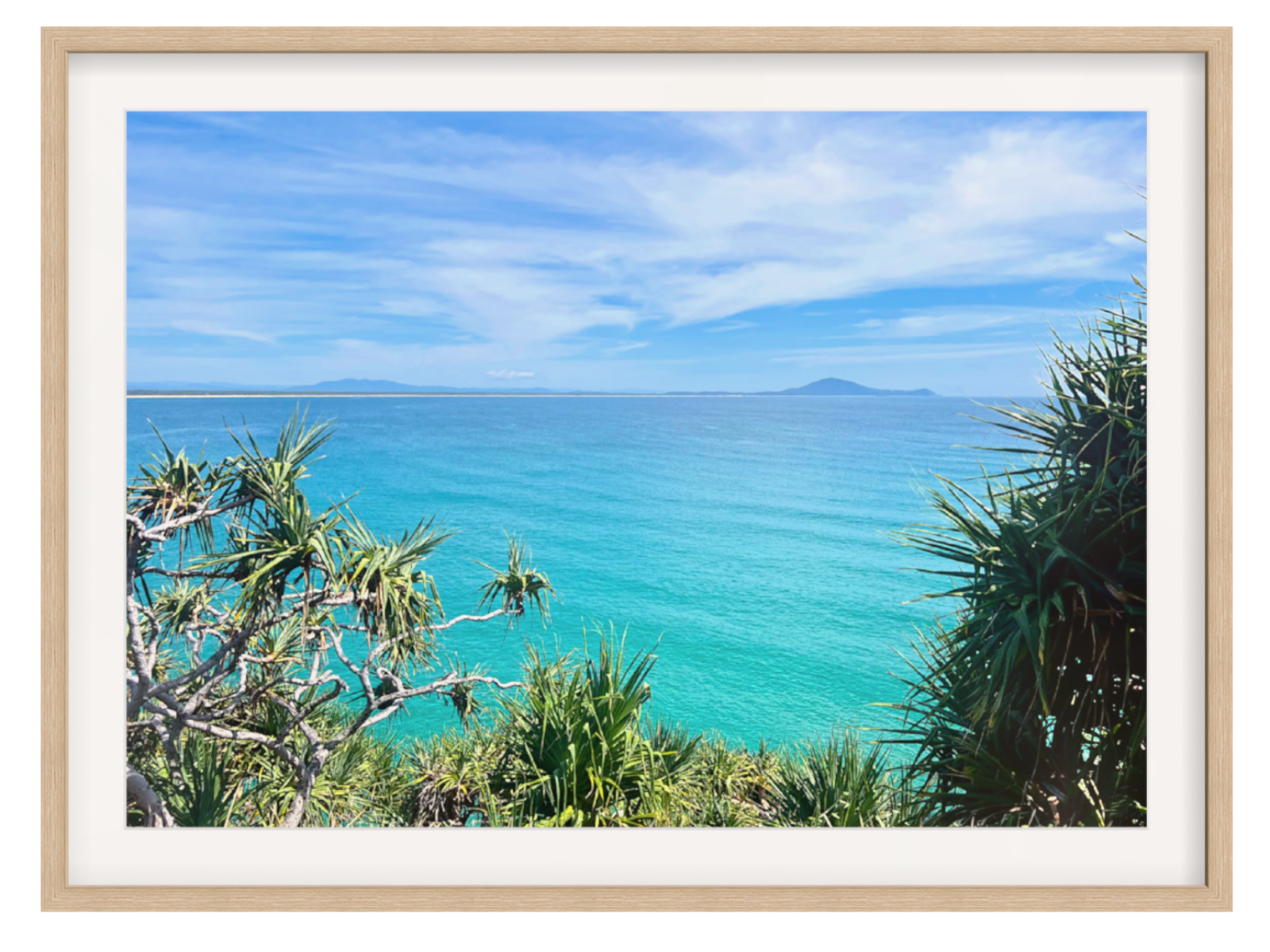 Framed photograph of a tropical landscape with turquoise ocean and palm trees.