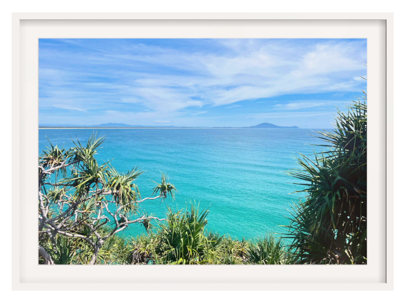 Framed photograph of a tropical beach with clear blue water and sky.