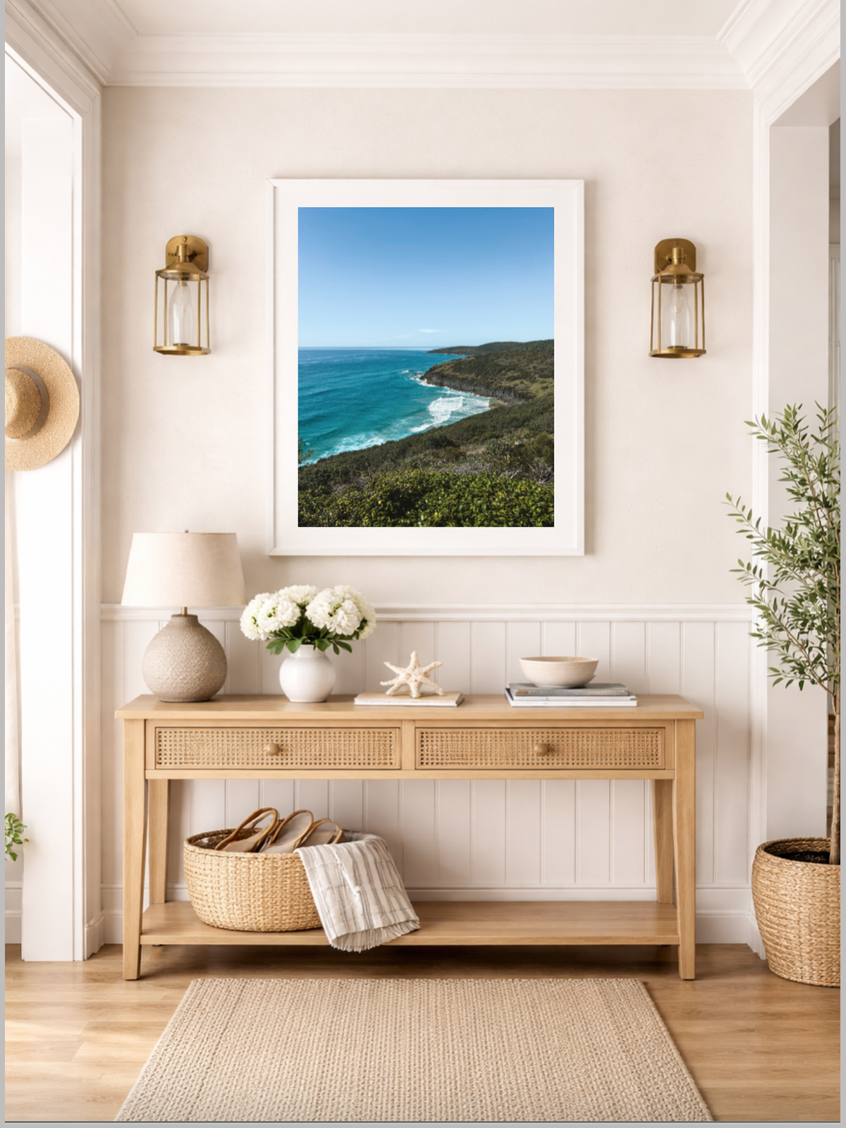 Hat Head Australia framed coastal print hanging on beige wall above console table styled with gold sconces