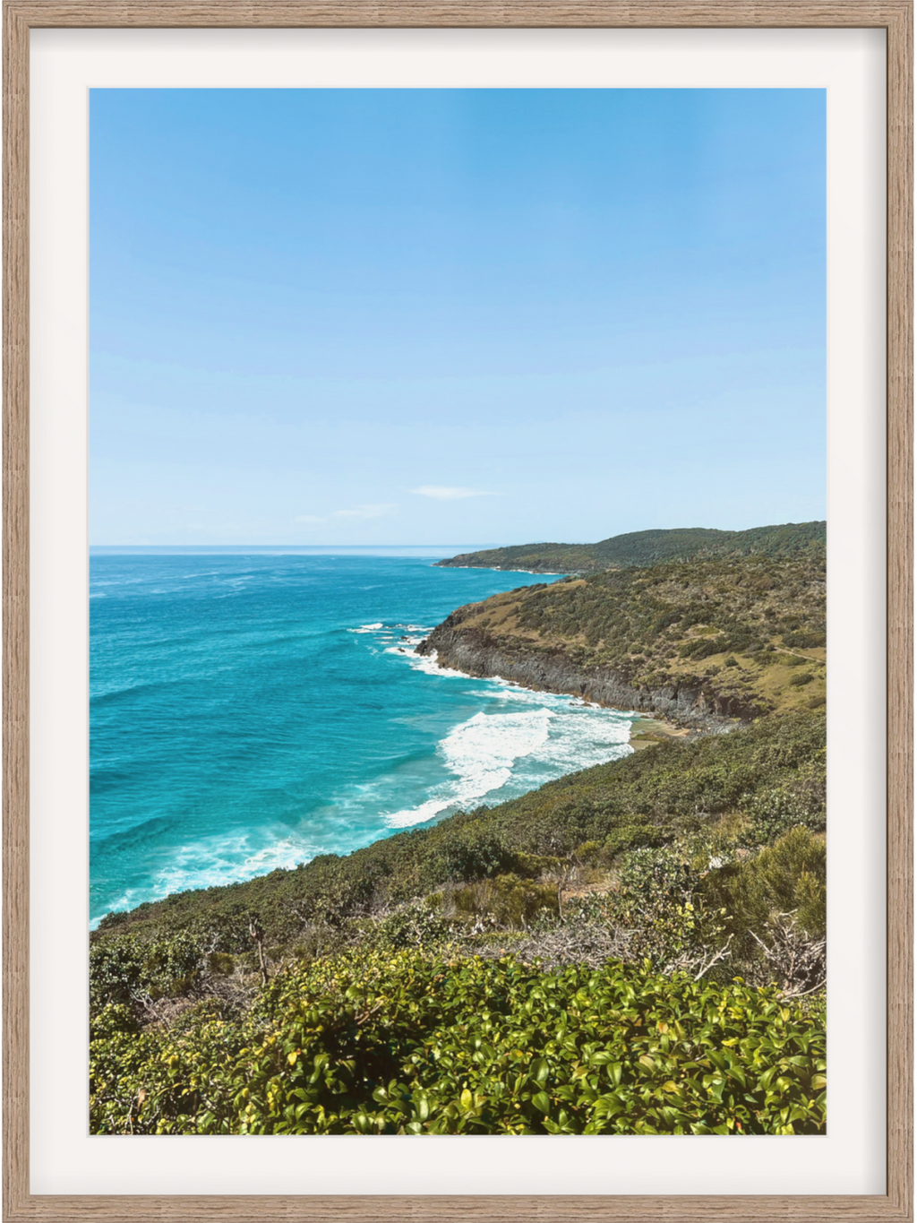 Hat Head Australia framed wall art in light wood with white mat featuring clear blue sky and breaking waves
