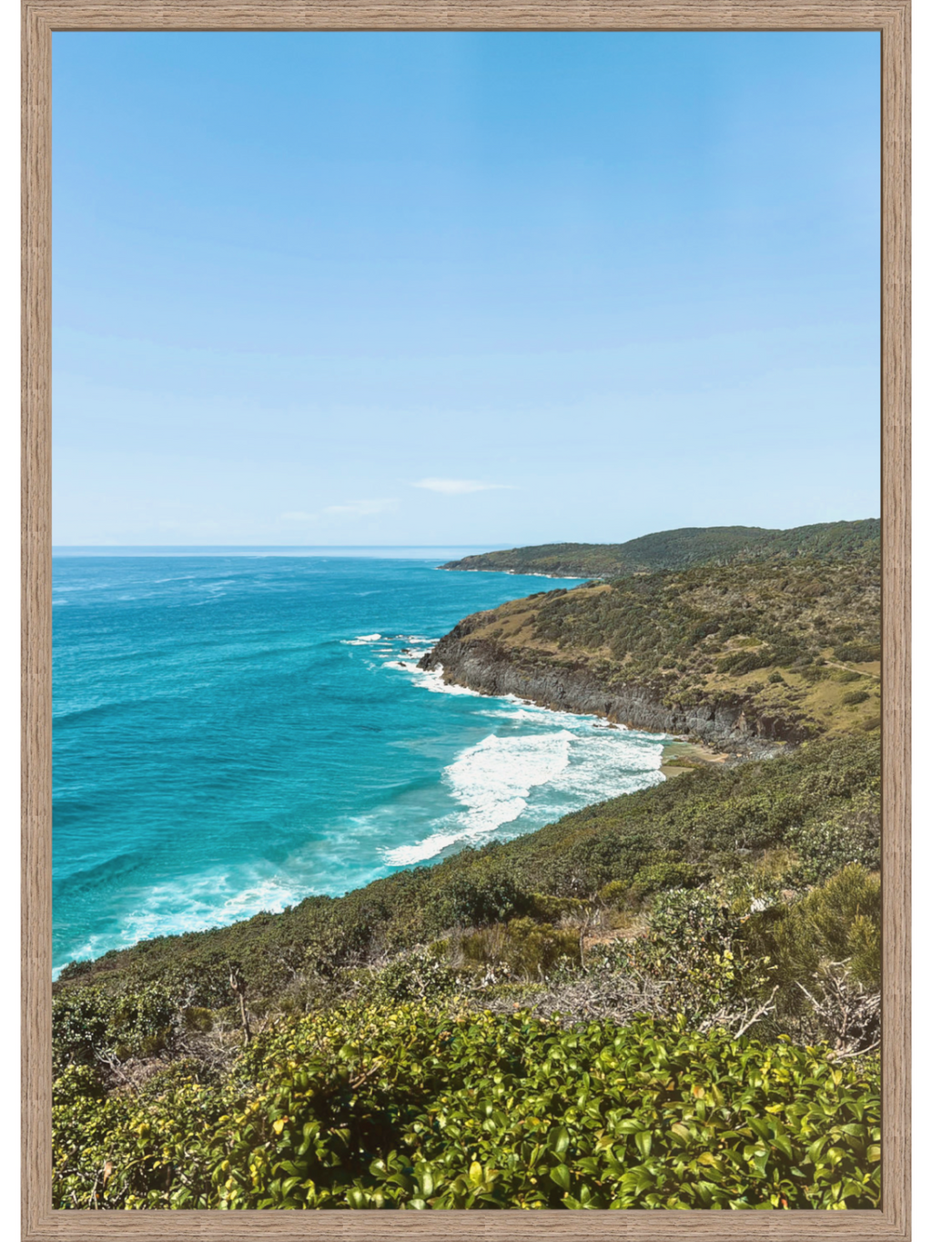 Vertical Hat Head Australia print in light grain wood frame emphasizing sweeping curve of turquoise coastline
