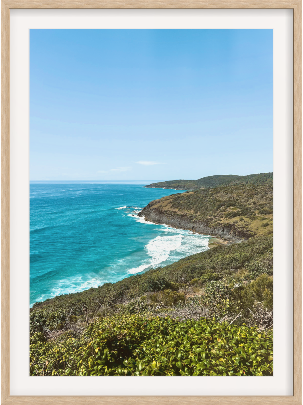 Hat Head Australia framed print in light wood with white mat showing lush foreground foliage and blue sky