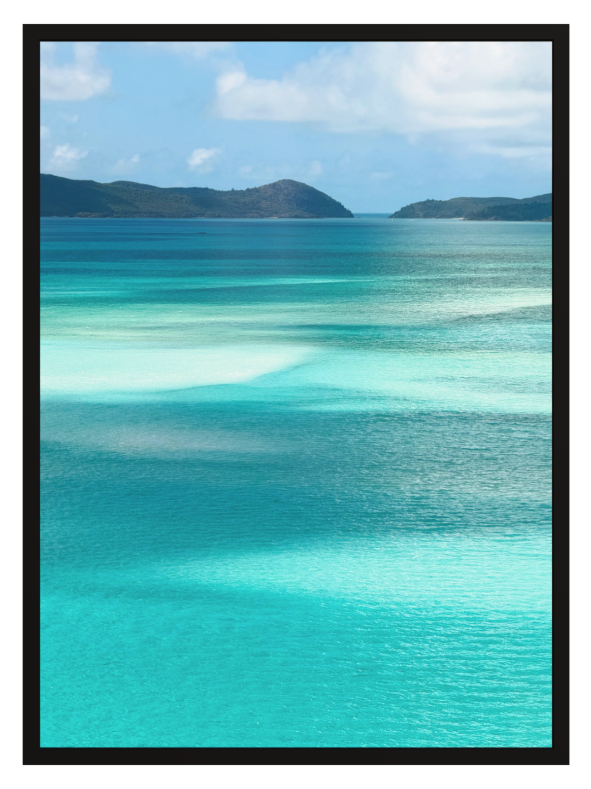 Scenic view of turquoise ocean water with shallow clear pools, distant dark green hills, and a blue sky with white clouds. black frame