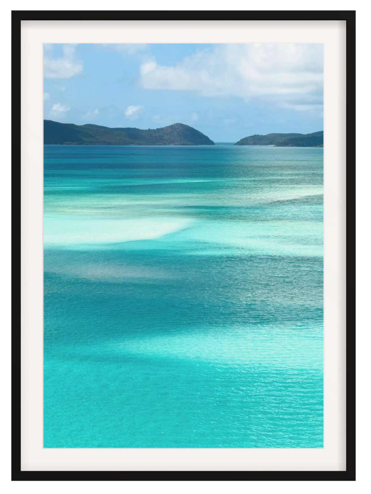 Scenic view of turquoise ocean water with shallow clear pools, distant dark green hills, and a blue sky with white clouds. black frame