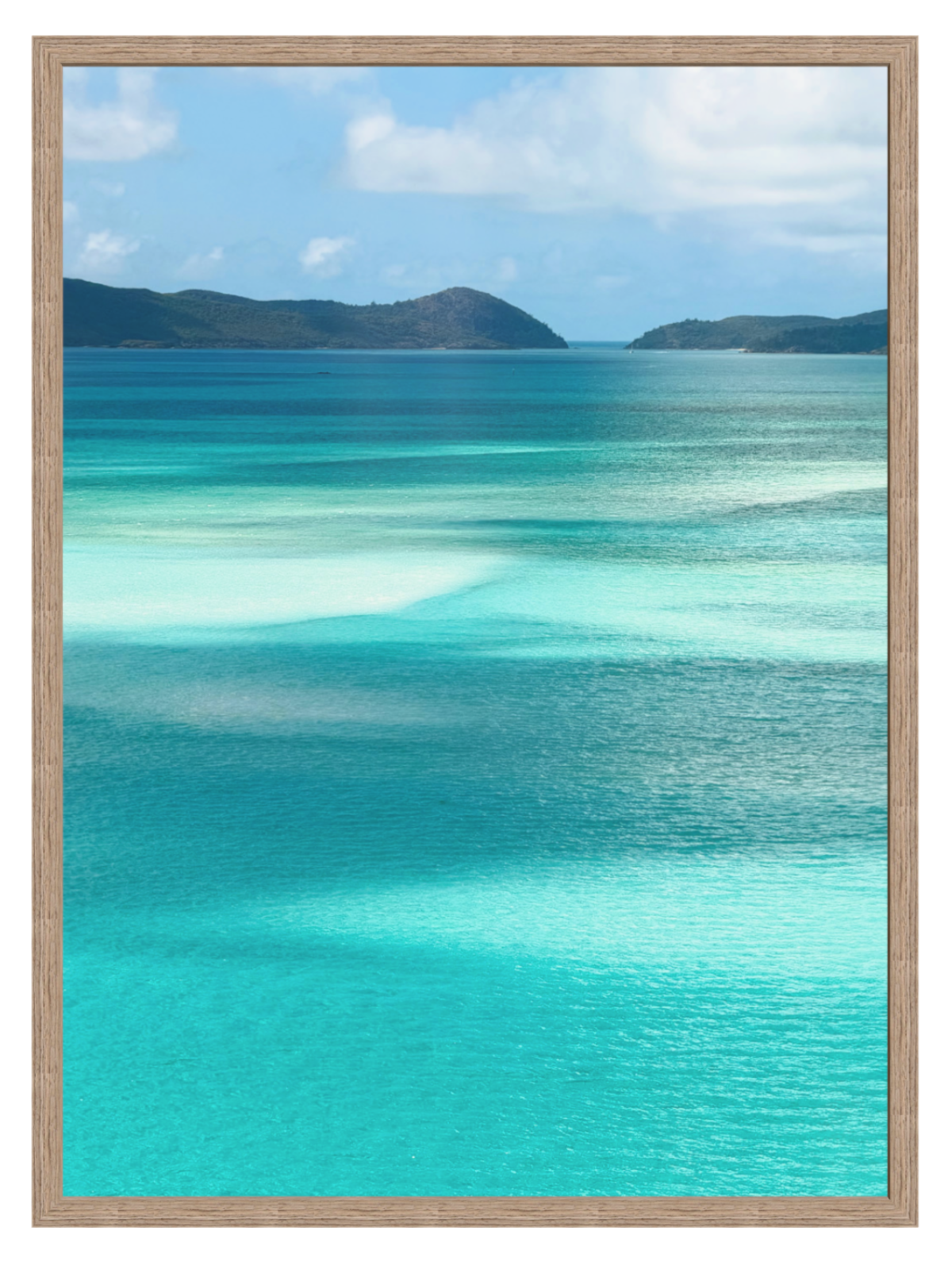 Scenic view of turquoise ocean water with shallow clear pools, distant dark green hills, and a blue sky with white clouds. hazel frame