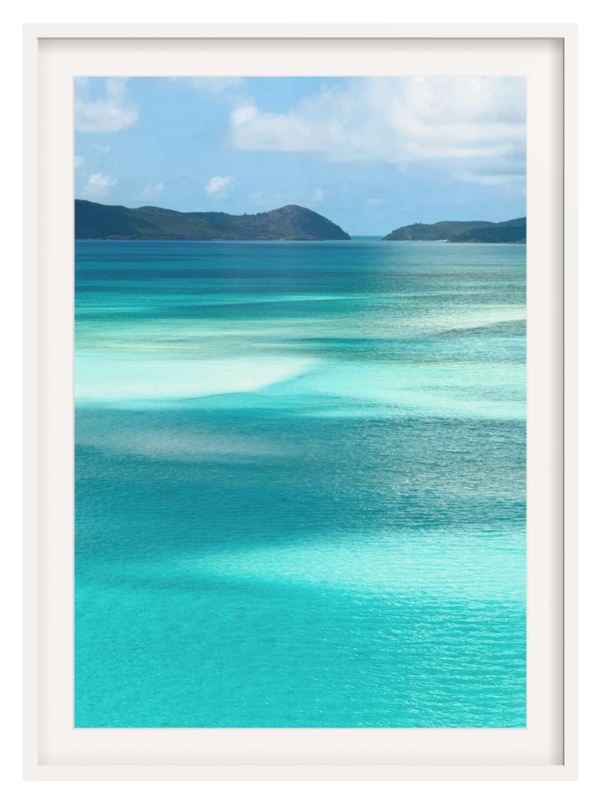 Scenic view of turquoise ocean water with shallow clear pools, distant dark green hills, and a blue sky with white clouds. white frame