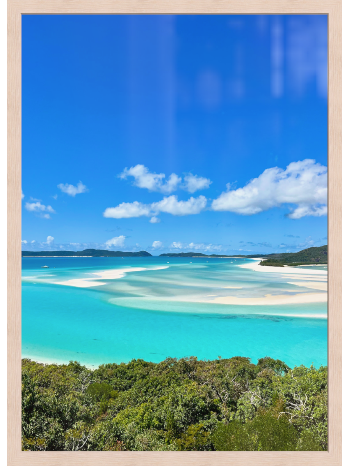 Turquoise waters and white sand beach with blue sky and green trees.