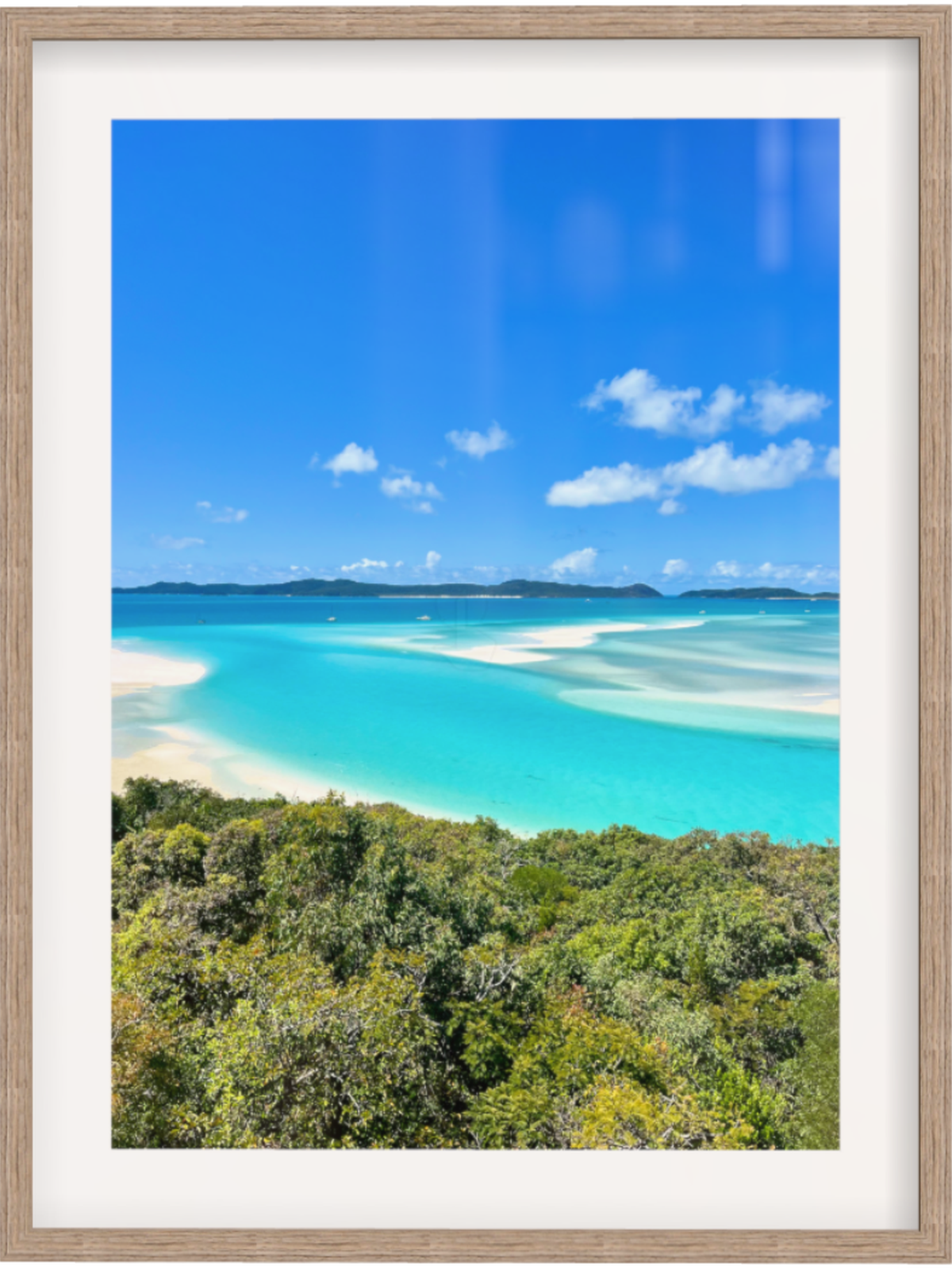 Framed photograph of a tropical beach with clear blue water and greenery.