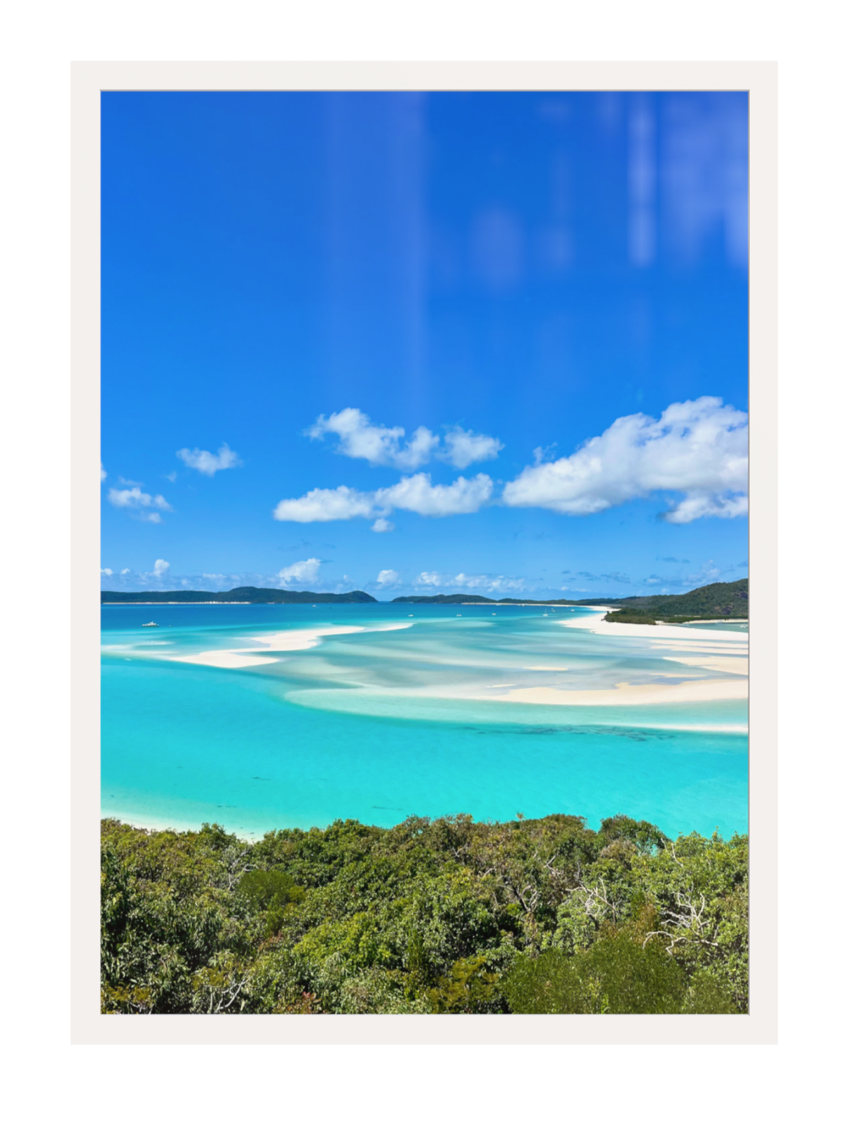 Scenic view of a tropical beach with turquoise water and white sand, framed by a white border.