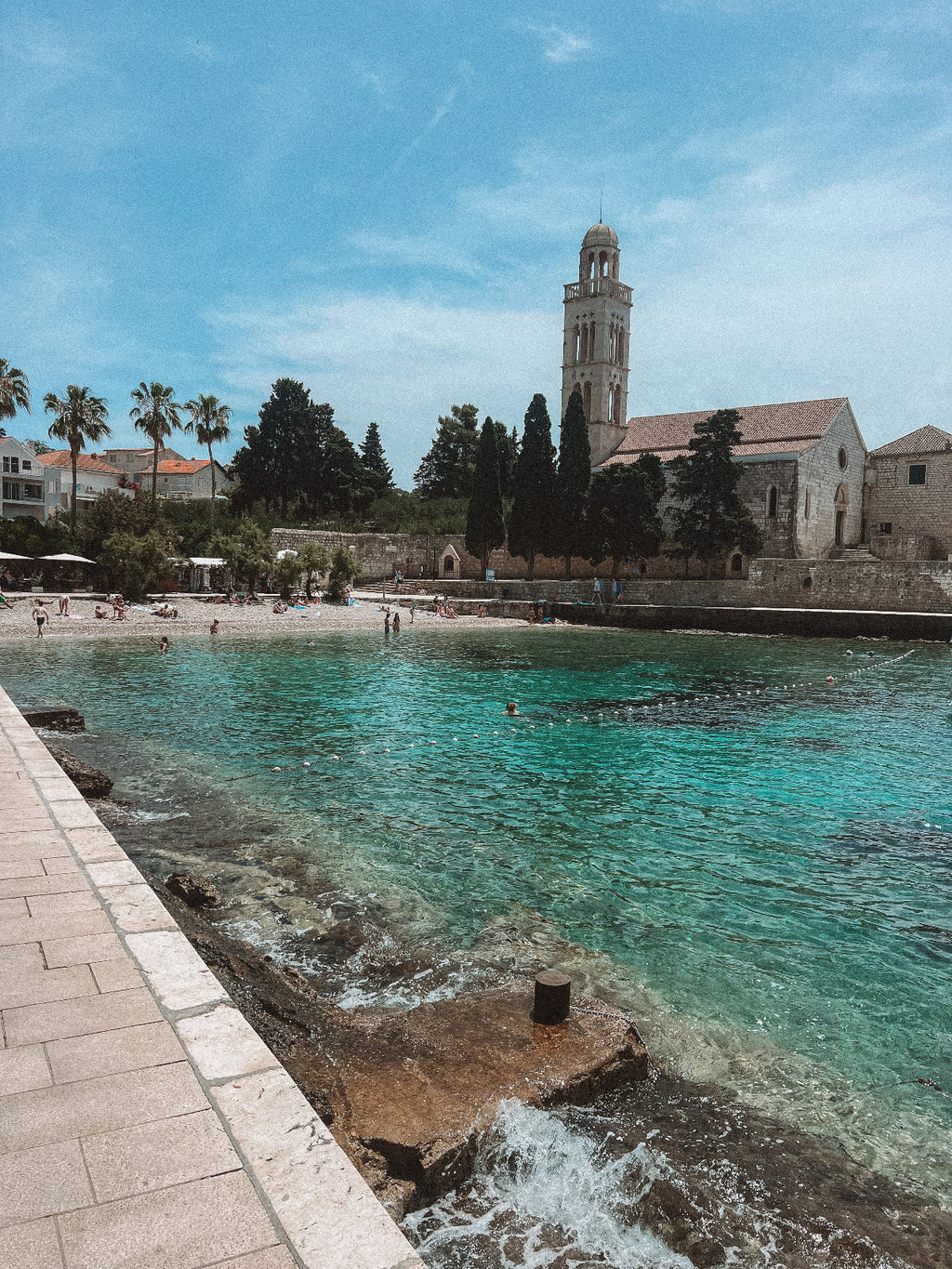 Coastal scene with a church and beach, under a clear blue sky.