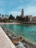 Coastal scene with a church and beach, under a clear blue sky.